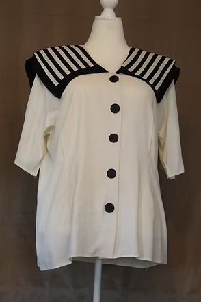White short-sleeve blouse on mannequin with large black-striped collar and black buttons