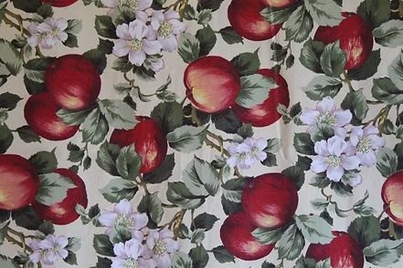 Floral fabric with red apples and pale purple blossoms on a light background