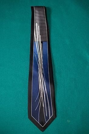 Black necktie with a blue geometric pattern and silver diagonal lines on a teal background