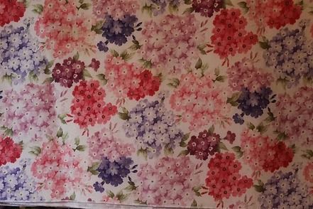Floral fabric pattern with red, pink, purple, and white blossoms on a beige background