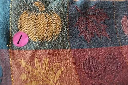 Colorful embroidered fabric with autumn leaves and a pink button marker on the left
