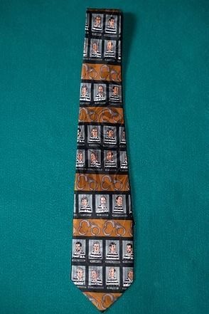 Black necktie with orange and white patterned panels on a teal background