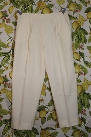 Cream-colored pants laid flat on a leafy patterned background.