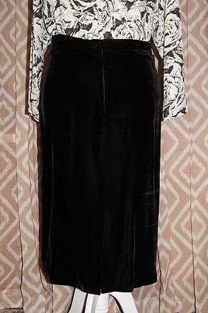 Black skirt with white floral long-sleeve top hanging against patterned wallpaper.