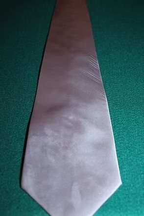 Light gray necktie on a green textured surface.