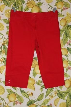 Bright red pants laid flat on a fruit-patterned tablecloth.