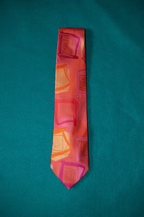 Colorful pink and orange necktie on a teal background