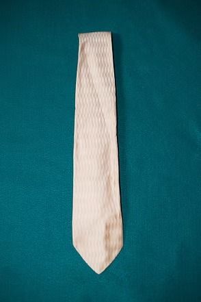 Beige striped necktie on a teal background