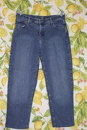 Blue jeans laid flat on a patterned lemon-and-leaf background.