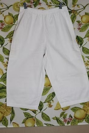 White pants laid flat on a patterned leaf-print surface.