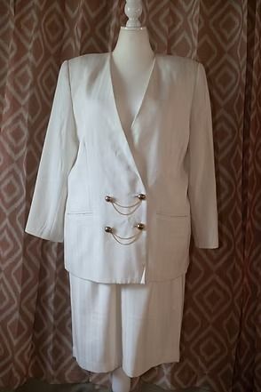 White suit jacket and skirt displayed on a mannequin against a patterned brown backdrop