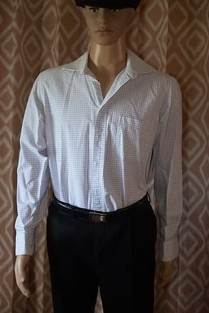 Mannequin wearing a white checkered shirt and black pants against a patterned curtain backdrop