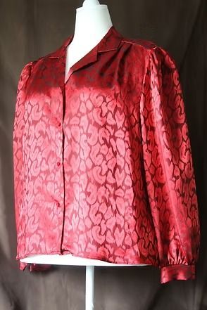 Red patterned satin jacket on a mannequin, with long sleeves and a collared neckline