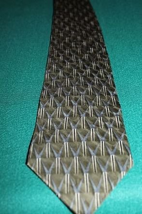 Patterned metal tie clip on a teal surface