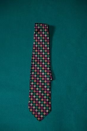 Patterned necktie with pink, green, and black diamond shapes on a teal background
