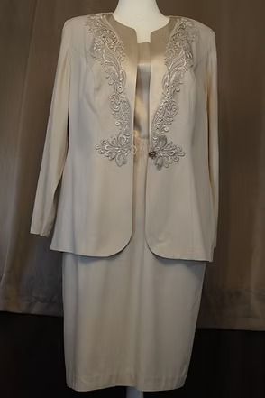 Cream-colored embroidered jacket and skirt displayed on a mannequin.