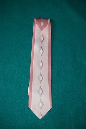 Pink necktie with white diamond pattern on green background
