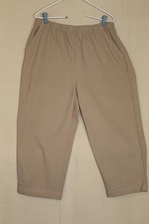 Beige pants hanging on a hanger against a plain background