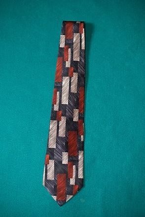 Patterned necktie in red, gray, white, and black on a teal background