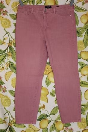 Pink pants laid flat on a patterned surface with green leaves and lemons.