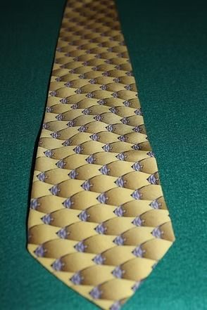 Yellow and blue patterned necktie on green fabric background