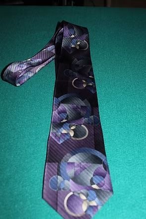 Purple patterned necktie on a green surface