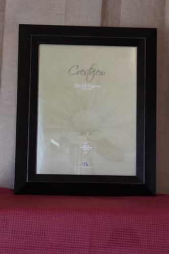 Black framed certificate or photo on a beige wall above a red surface