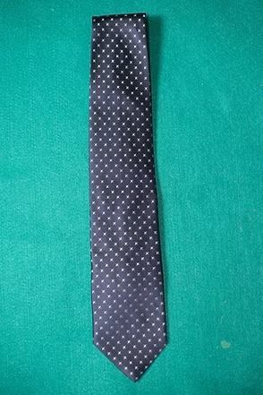 Black polka dot necktie on a green background