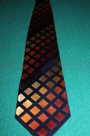 Red and orange diamond-pattern necktie on a teal background