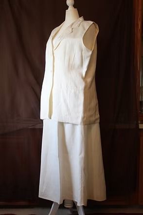 White sleeveless dress on a mannequin against a dark background.
