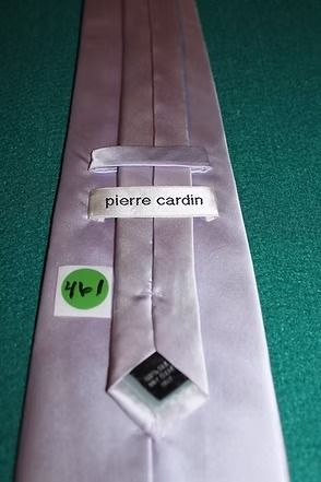 Light gray necktie on a green textured surface.