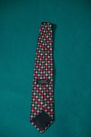 Patterned necktie with pink, green, and black diamond shapes on a teal background