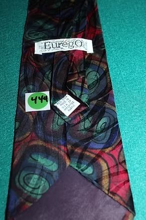 Colorful patterned necktie with red, green, and blue swirls on a teal surface
