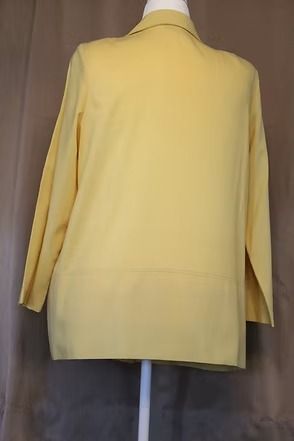 Yellow blazer jacket displayed on a mannequin against a dark background