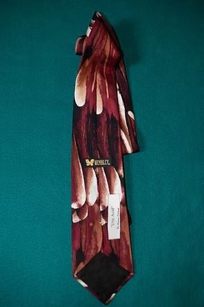 Maroon patterned necktie with white and tan leaf-like shapes on a teal background