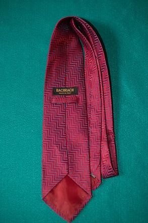 Red patterned necktie on a teal background