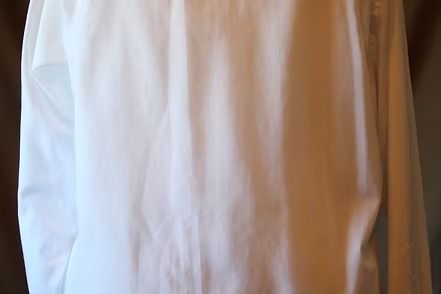 Close-up of a white dress shirt sleeve being rolled up by a hand