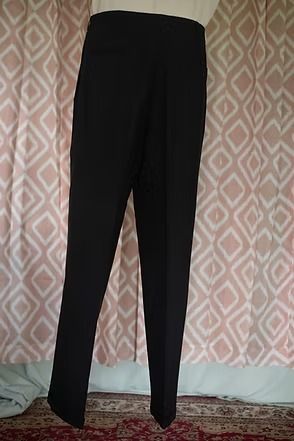 Black trousers hanging against a patterned wall.