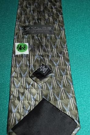 Patterned metal tie clip on a teal surface