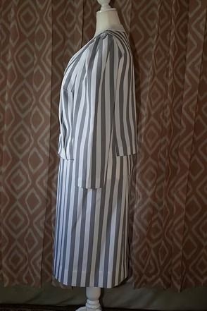Striped long coat on a mannequin against a patterned curtain.