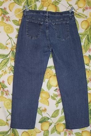 Blue jeans laid flat on a patterned lemon-and-leaf background.