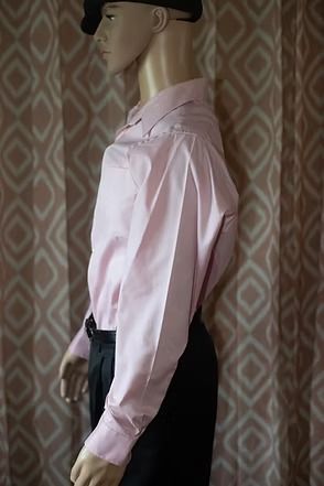 Mannequin wearing a pink dress shirt, black pants, and black beret against a patterned backdrop