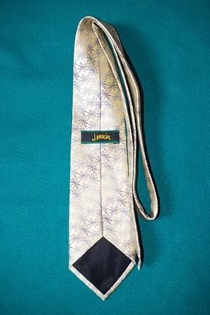 Light gold patterned necktie on a teal background