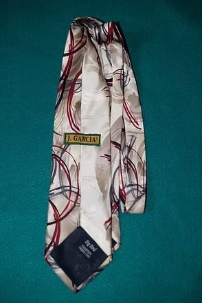 White necktie with red, black, and gray circular pattern on a teal background