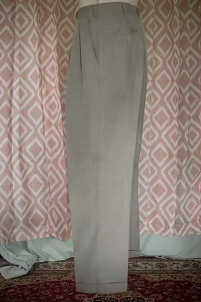 Gray trousers hanging against a patterned curtain indoors
