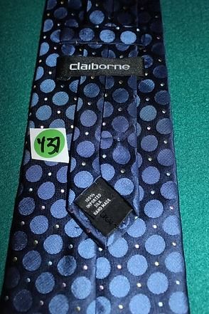 Black necktie with blue polka dots on a green surface