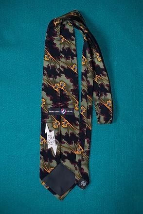 Narrow patterned necktie with blue, yellow, and burgundy zigzag design on a teal background