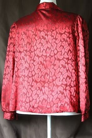 Red patterned satin jacket on a mannequin, with long sleeves and a collared neckline