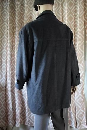 Mannequin wearing a black coat and beret against patterned curtains
