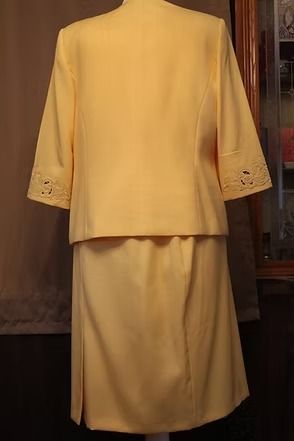 Yellow embroidered two-piece suit with buttoned jacket and long skirt on a mannequin